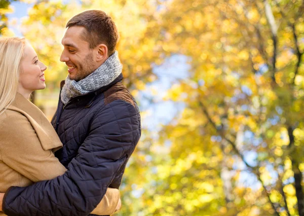 Lachende paar knuffelen over herfst achtergrond — Stockfoto