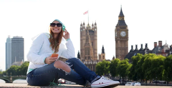 Счастливая молодая женщина со смартфоном и наушниками — стоковое фото