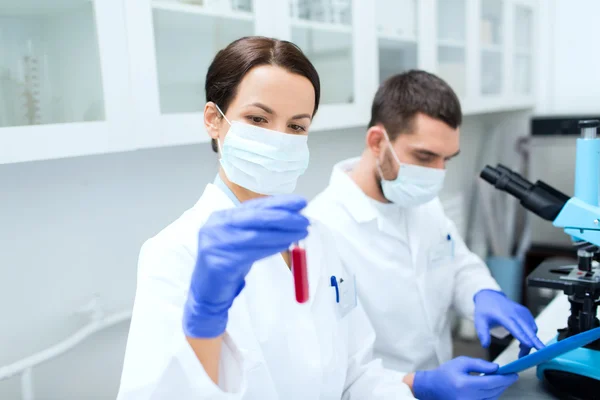 Jovens cientistas que fazem testes ou pesquisas em laboratório — Fotografia de Stock