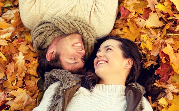 Close up of smiling couple lying in autumn park — Stock Photo, Image