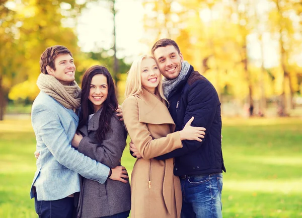 Group of smiling men and women in autumn park — Stock Photo, Image