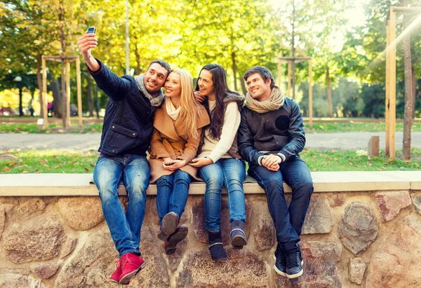 Amis souriants avec smartphones dans le parc de la ville — Photo