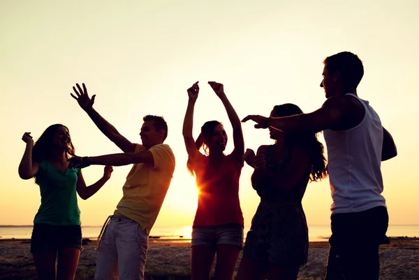 Uśmiechnięty znajomych tańce na plaży latem — Zdjęcie stockowe