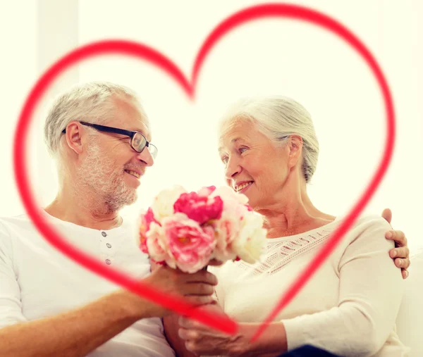 Happy senior couple with bunch of flowers at home — Stock Photo, Image