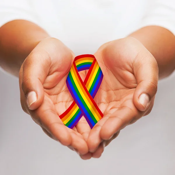 Hands holding rainbow gay pride awareness ribbon — Stock Photo, Image