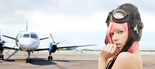 Girl in aviator helmet over plane at airport — Stockfoto