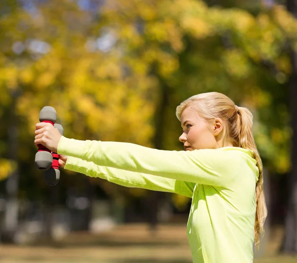 Sporty woman with light dumbbells outdoors — Stock Photo, Image