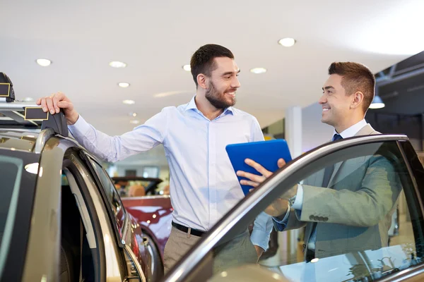 Homem feliz com negociante de carro em auto show ou salão de beleza — Fotografia de Stock