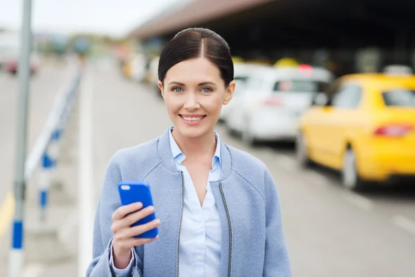 Smiling woman with smartphone over taxi in city — Stock Photo, Image