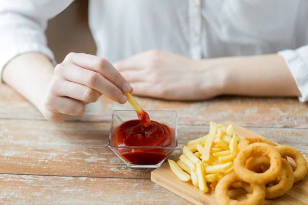 フライド ポテトをケチャップに浸漬の手のクローズ アップ — ストック写真