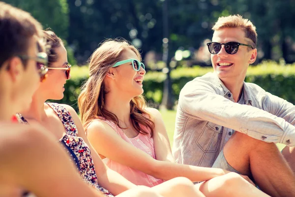 Группа улыбающихся друзей на открытом воздухе, сидящих в парке — стоковое фото