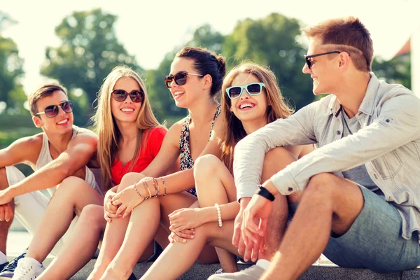 Группа улыбающихся друзей, сидящих на городской улице — стоковое фото