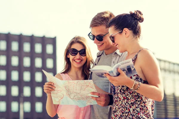 Smiling friends with map and city guide outdoors — Stock Photo, Image