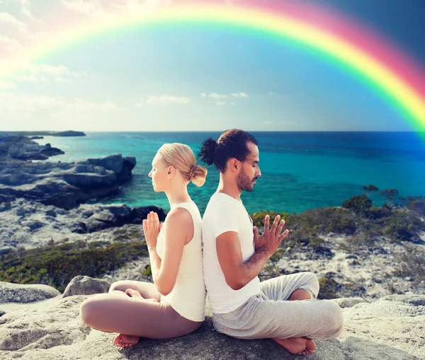 Casal feliz meditando em lótus posar na praia — Fotografia de Stock