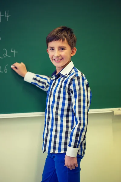 Kleiner lächelnder Schuljunge, der auf Kreidetafel schreibt — Stockfoto