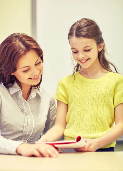 Schulmädchen mit Notizbuch und Lehrer im Klassenzimmer — Stockfoto