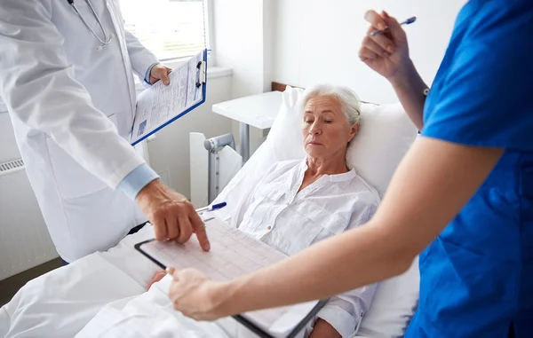 Médico e enfermeira visitando mulher idosa no hospital — Fotografia de Stock