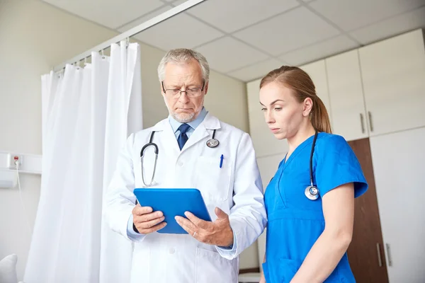 Médico senior y enfermera con tableta pc en el hospital — Foto de Stock