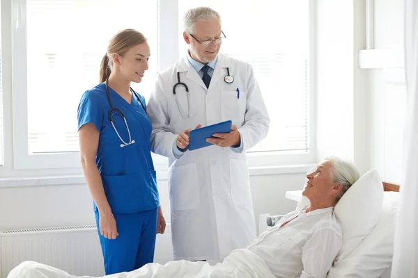 Médico y enfermera visitando a una mujer mayor en el hospital —  Fotos de Stock