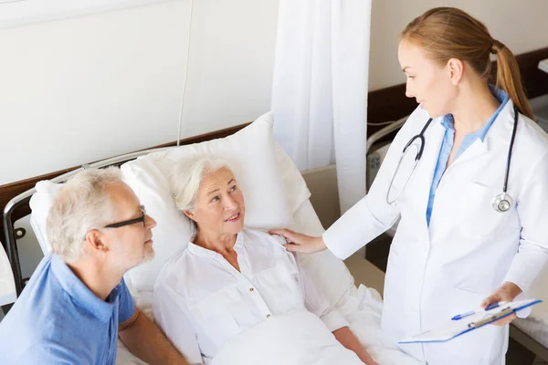 Senior woman and doctor with clipboard at hospital — Stock Photo, Image