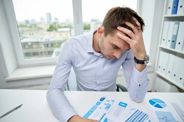 Stressad affärsman med papper i office — Stockfoto