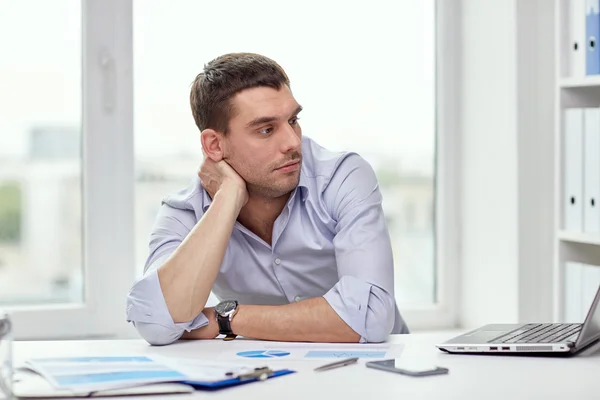 Uomo d'affari annoiato con computer portatile e carte in ufficio — Foto Stock