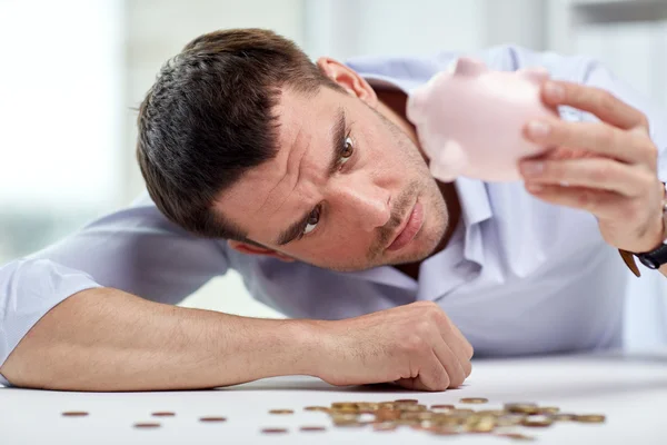 Hombre de negocios con alcancía y monedas en la oficina — Foto de Stock