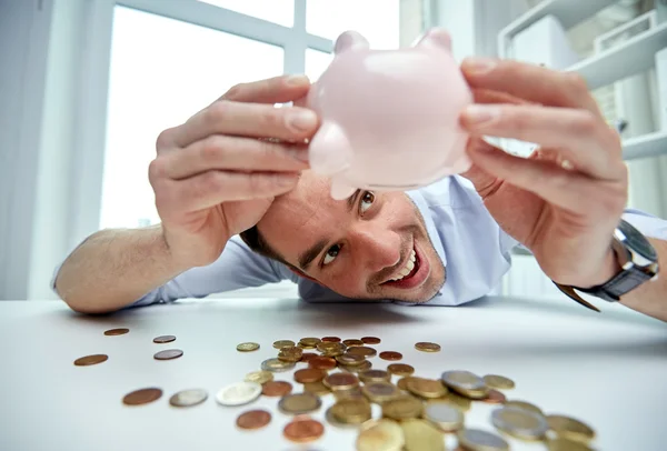 Hombre de negocios con alcancía y monedas en la oficina — Foto de Stock