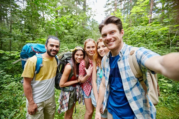 Przyjaciele z plecaka biorąc selfie w drewnie — Zdjęcie stockowe