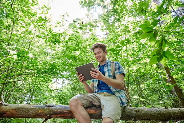 Glücklicher Mann mit Rucksack und Tablet-PC im Wald — Stockfoto