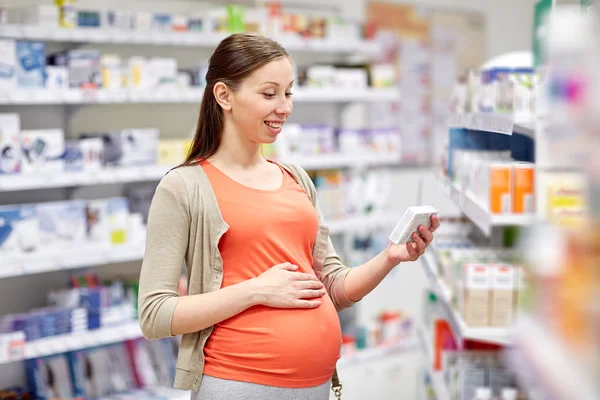 Gelukkig zwangere vrouw met medicatie bij apotheek — Stockfoto