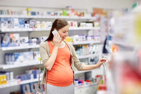 Gelukkig zwangere vrouw met smartphone bij apotheek — Stockfoto