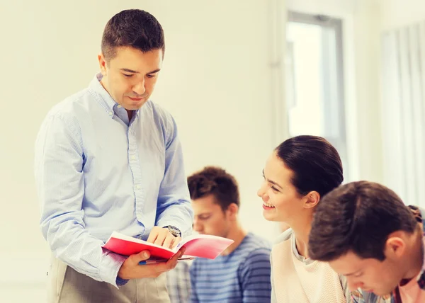 Group of students and teacher with notebook — Stock Photo, Image