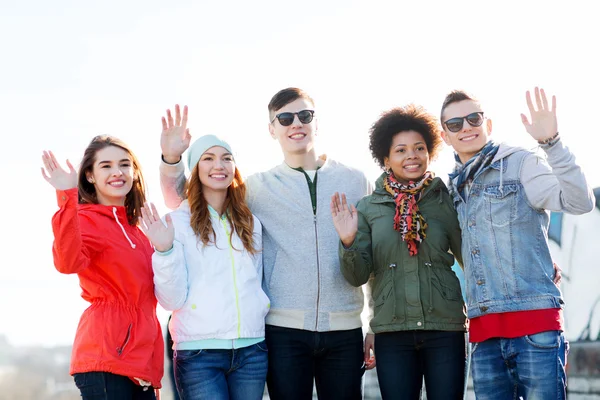 Happy teenage friends waving hands on city street — Stock Photo, Image