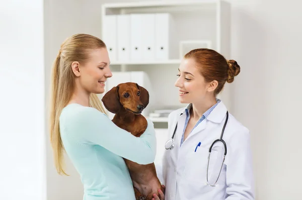 Mulher feliz com cão e médico na clínica veterinária — Fotografia de Stock