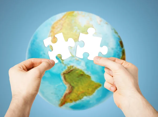 Handen met witte lege puzzel over earth globe — Stockfoto