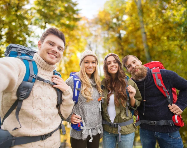 Skupina usměvavá přátel s batohy turistika — Stock fotografie