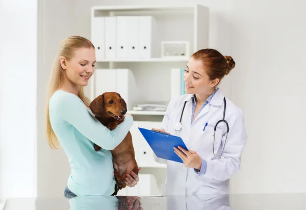 Mulher feliz com cão e médico na clínica veterinária — Fotografia de Stock