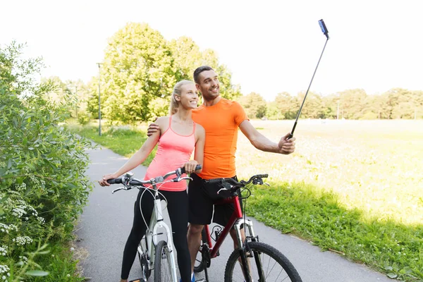 Casal com bicicleta e vara selfie smartphone — Fotografia de Stock