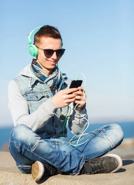 Joven feliz en auriculares con teléfono inteligente — Foto de Stock