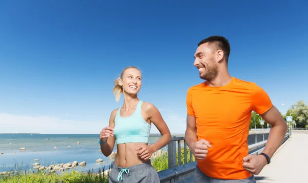 Couple souriant courant au bord de la mer d'été — Photo