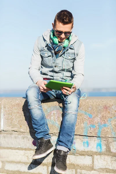 Счастливый молодой человек с планшетным ПК и наушниками — стоковое фото