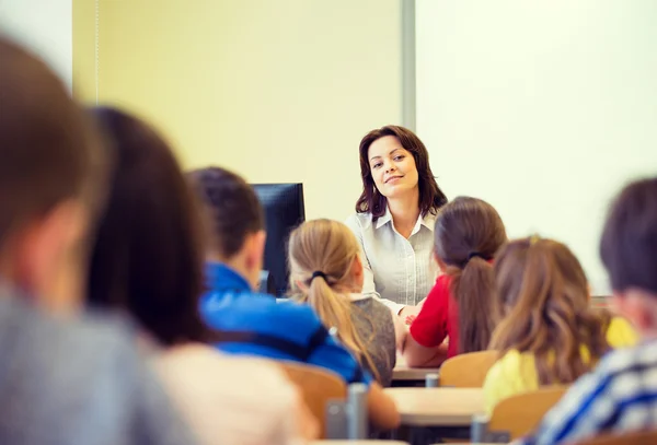 Grupp av skolan barnen höjande händer i klassrummet — Stockfoto