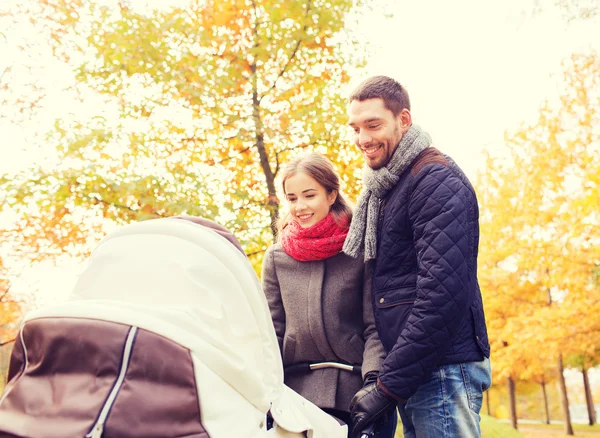 Casal sorridente com carrinho de bebê no parque de outono — Fotografia de Stock