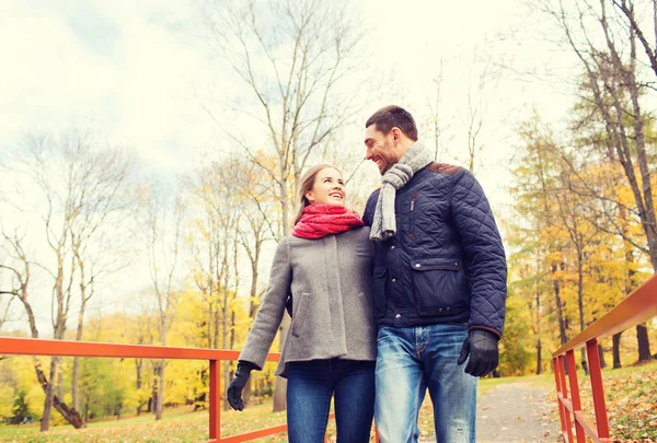 Lachende paar knuffelen op brug in herfst park — Stockfoto