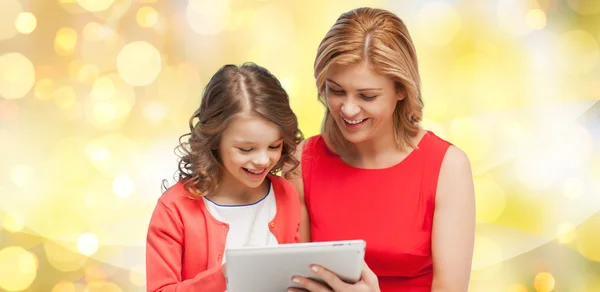 Mother and daughter with tablet pc over lights — 图库照片