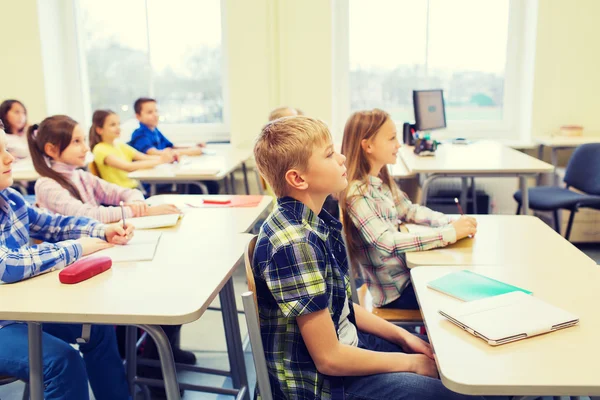 Grupo de escolares com cadernos em sala de aula — Fotografia de Stock