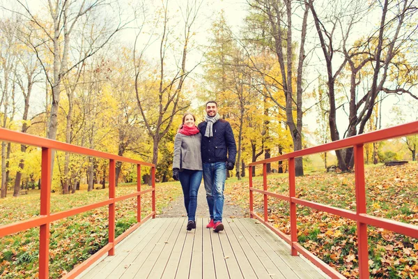 Pareja sonriente abrazándose en el puente en el parque de otoño — Foto de Stock