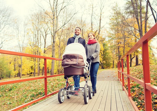 Couple souriant avec poussette bébé dans le parc d'automne — Photo