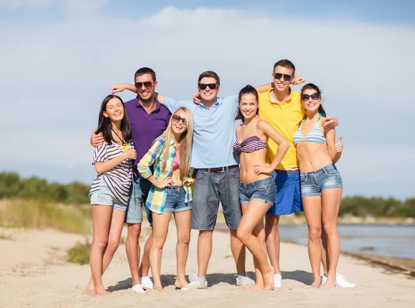 Gruppo di amici felici che si abbracciano sulla spiaggia — Foto Stock